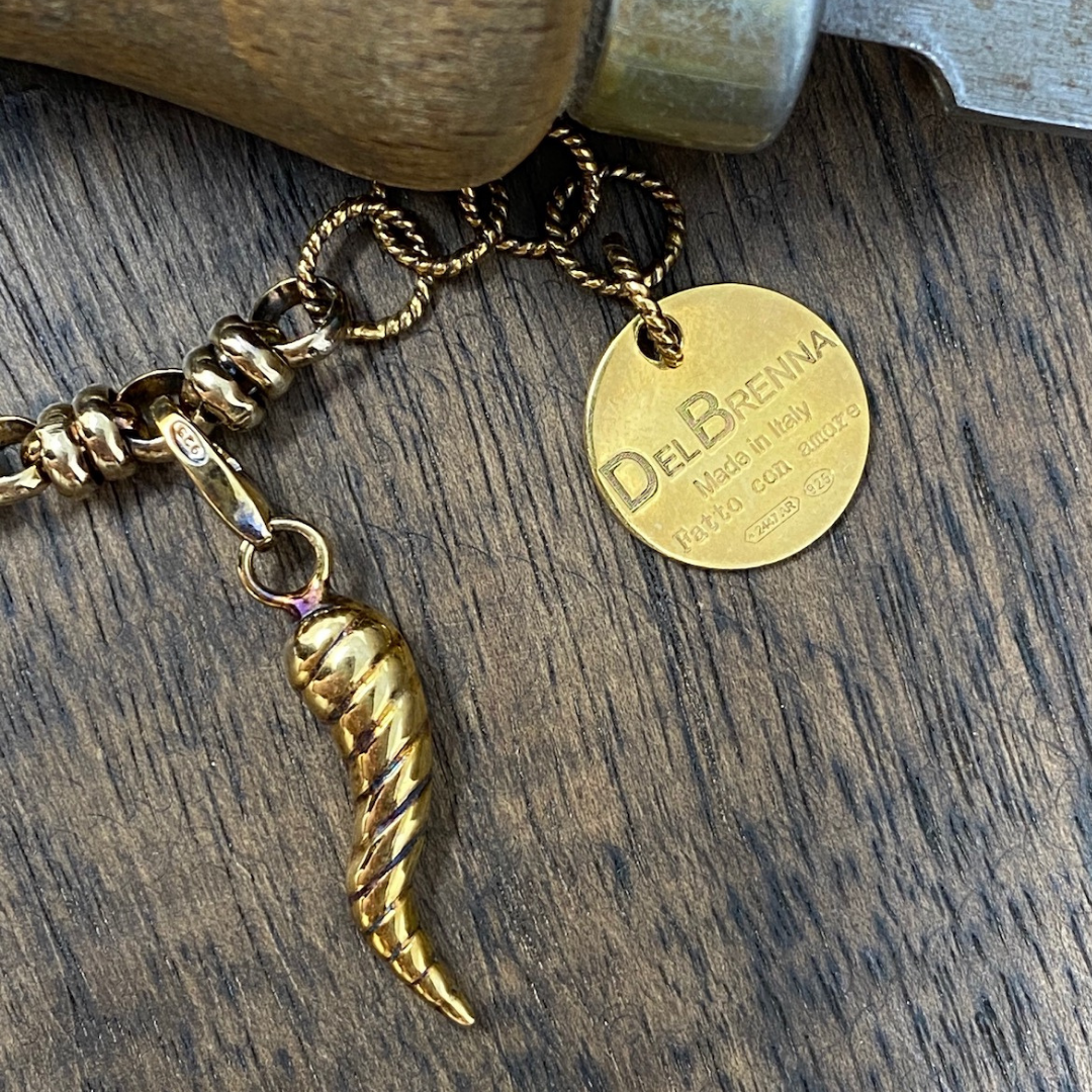 An Italian horn gold charm on a unique gold chain bracelet designed by DelBrenna Italian Jewelers.