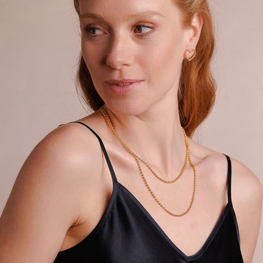 A model wearing two delicate, hand-crafted 2MM gold chains in two different lengths: a short, 16-18” gold chain necklace and a 20-22” gold necklace with matching gold heart earrings - all gold necklaces and earrings are crafted by DelBrenna Italian Jewelry designers in Tuscany.