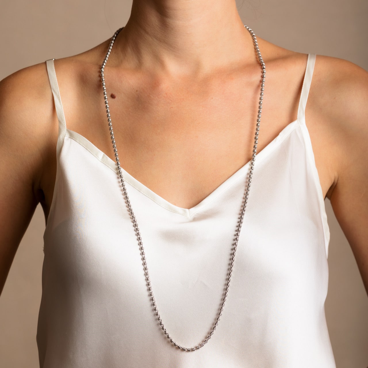 A model wearing a long (34-inch) DelBrenna Iconic Links 3mm silver necklace with matching Links 3mm silver earrings in the same chain design. Both pieces of hand-crafted Italian jewelry are made by DelBrenna Italian Jewelers in Tuscany.