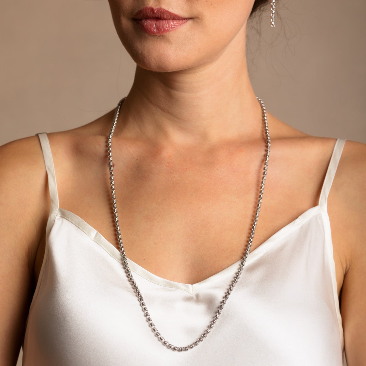 A model wearing a long (27-inch) DelBrenna Iconic Links 3mm silver necklace with matching Links 3mm silver earrings in the same chain design. Both pieces of hand-crafted Italian jewelry are made by DelBrenna Italian Jewelers in Tuscany.