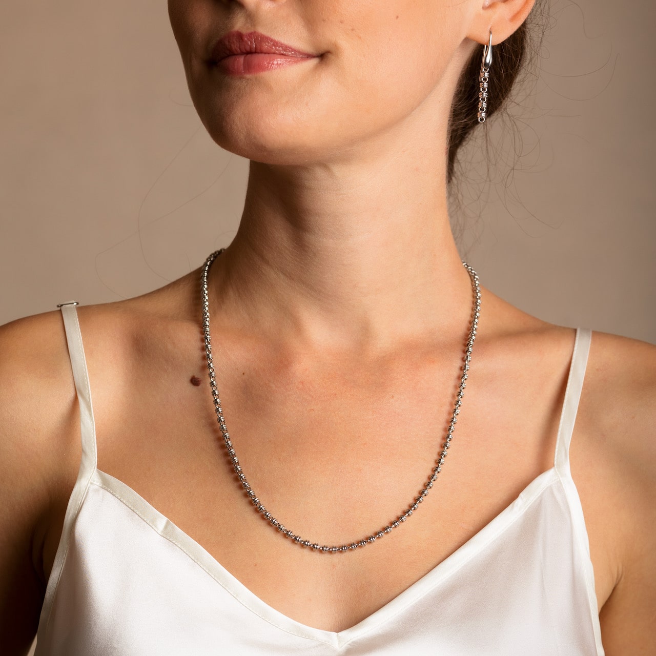 A model wearing a long (20-inch) DelBrenna Iconic Links 3mm silver necklace with matching Links 3mm silver earrings in the same chain design. Both pieces of hand-crafted Italian jewelry are made by DelBrenna Italian Jewelers in Tuscany.