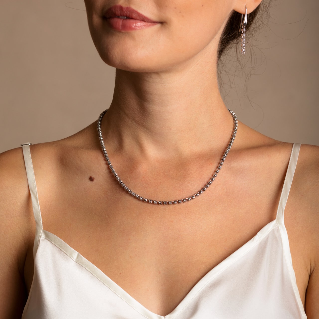 A model wearing a short (16-inch) DelBrenna Iconic Links 3mm silver necklace with matching Links 3mm large silver hoop earrings. Both pieces of hand-crafted Italian jewelry are made by DelBrenna Italian Jewelers in Tuscany.