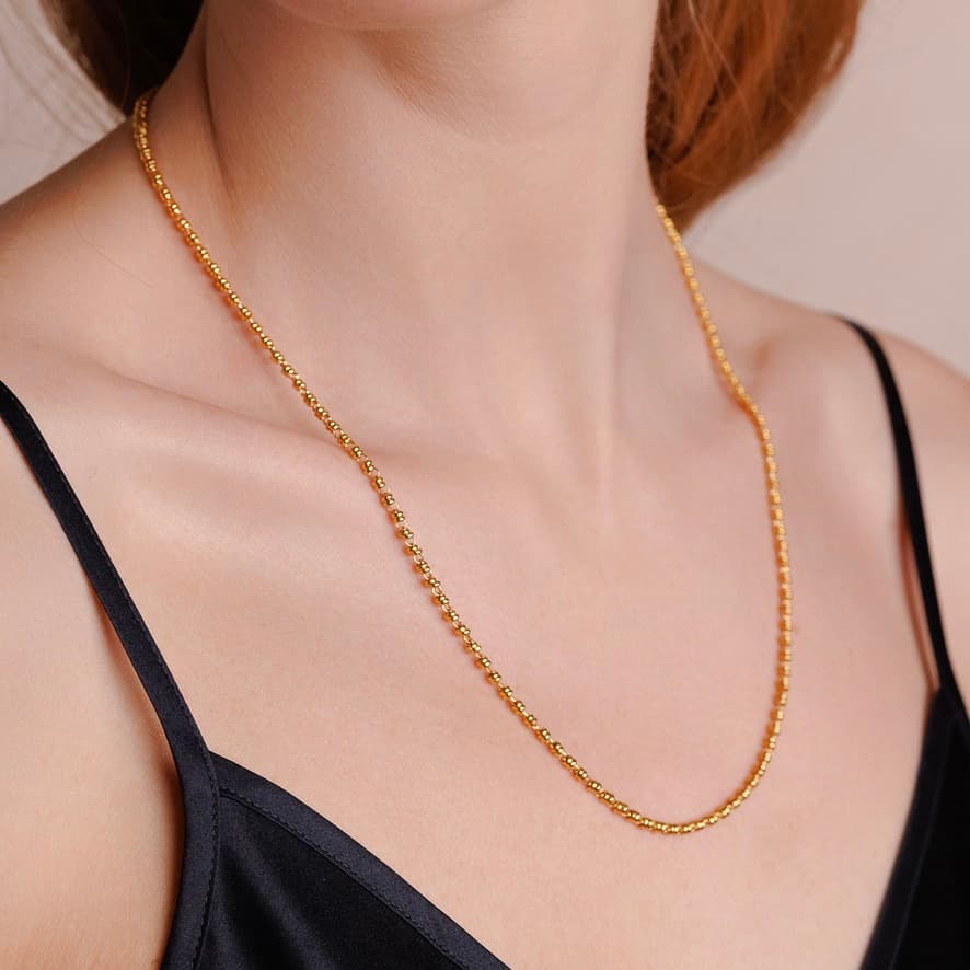 A left-facing, closeup view of a model wearing a short (18-inch) gold necklace. The necklace is a delicate 2MM version of the iconic gold chain designed by DelBrenna Italian jewelry designers in 1974 in Tuscany.