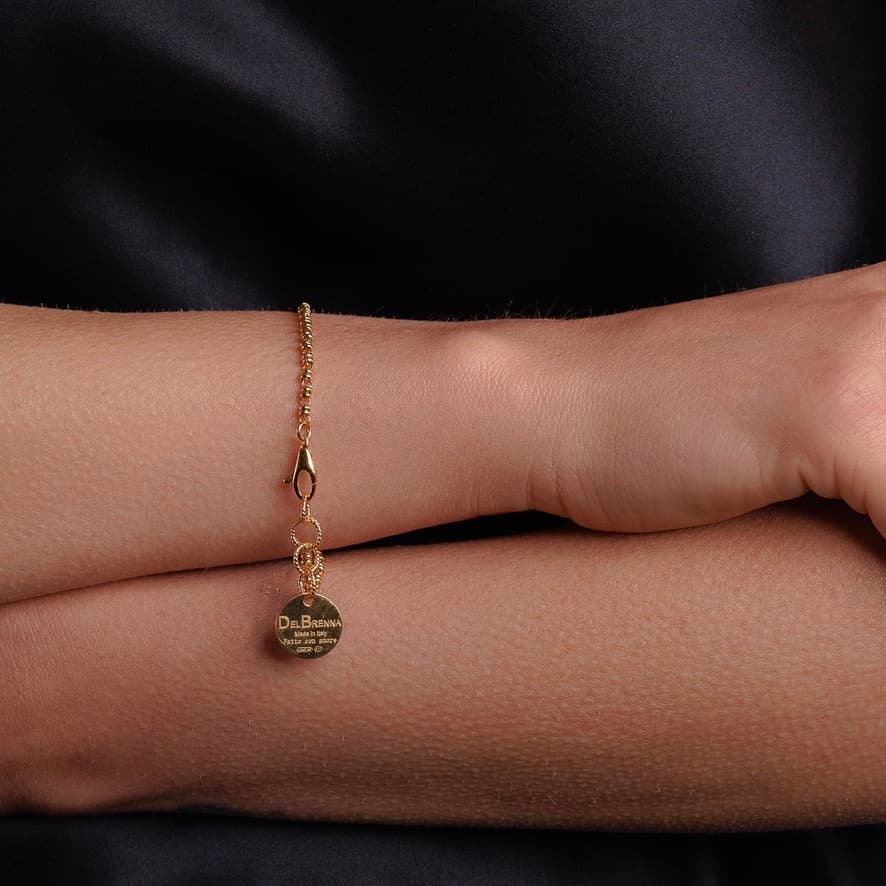 A model wearing a delicate gold chain bracelet with a small circular gold charm and lobster clasp all in 24K yellow gold finish over 925% sterling silver. The gold bracelet is designed from the iconic DelBrenna Links collection - Italian jewelry designs hand-crafted in Tuscany.