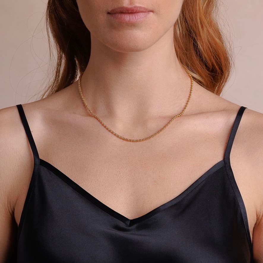 A front-facing, closeup view of a model wearing a short (16-inch) gold necklace. The necklace is a delicate 2MM version of the iconic gold chain designed by DelBrenna Italian jewelry designers in 1974 in Tuscany.