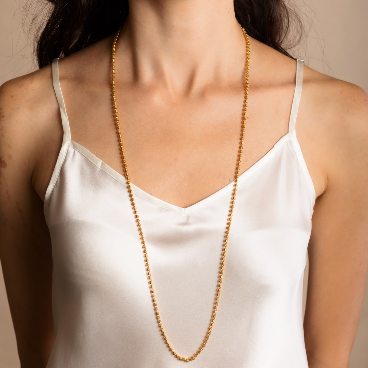 A model wearing a long (34-inch) DelBrenna Iconic Links 3MM gold necklace with matching Links 3MM large gold hoop earrings. Both pieces of hand-crafted Italian jewelry are made by DelBrenna Italian Jewelers in Tuscany. 