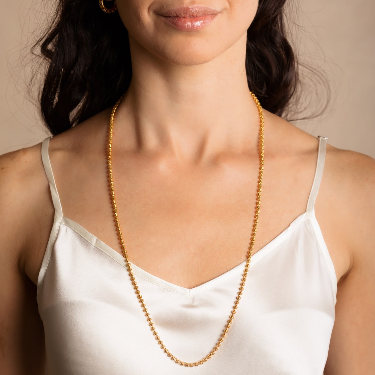 A model wearing a long (27-inch) DelBrenna Iconic Links 3MM gold necklace with matching Links 3MM large gold hoop earrings. Both pieces of hand-crafted Italian jewelry are made by DelBrenna Italian Jewelers in Tuscany.