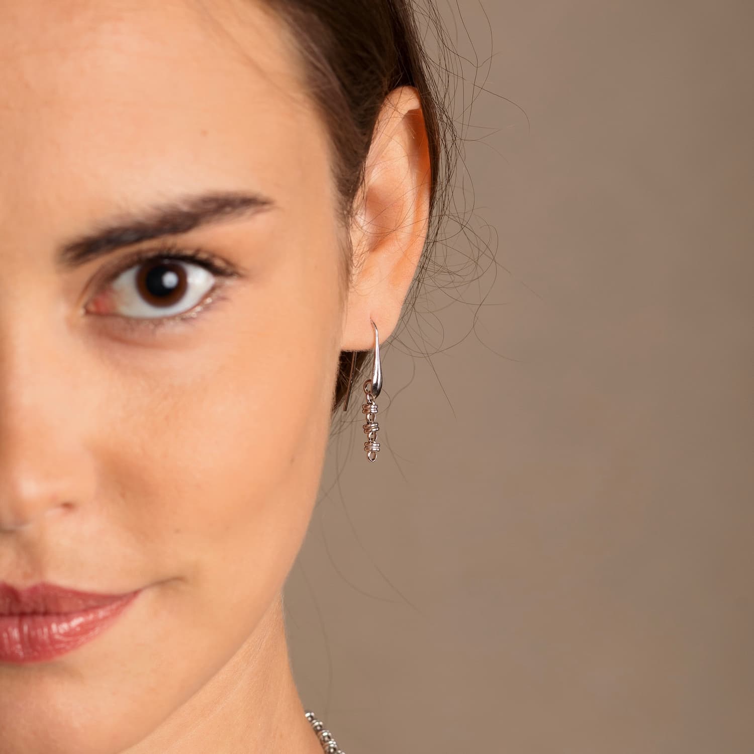 A closeup of a model wearing silver chain earrings designed and hand-crafted by DelBrenna Italian Jewelers in Tuscany. The earrings are designed based on the iconic Links collection of DelBrenna silver chains, necklaces, rings, and bracelets.