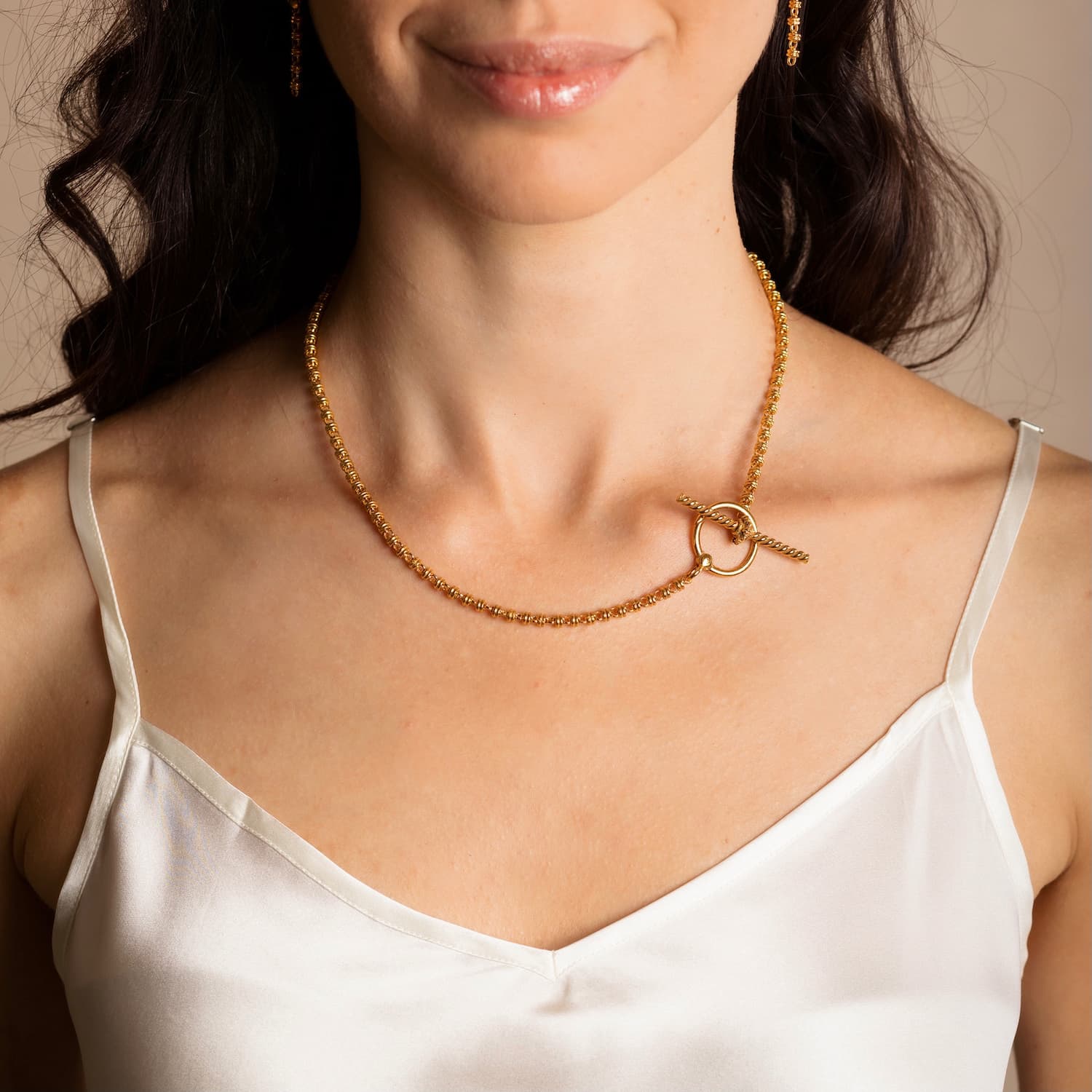 A model wearing a gold necklace with a toggle clasp and gold earrings to match the gold chain in the necklace design - both are from the Links 3mm collection from DelBrenna Italian Jewelry designers and artisans. Hand-crafted in Tuscany.