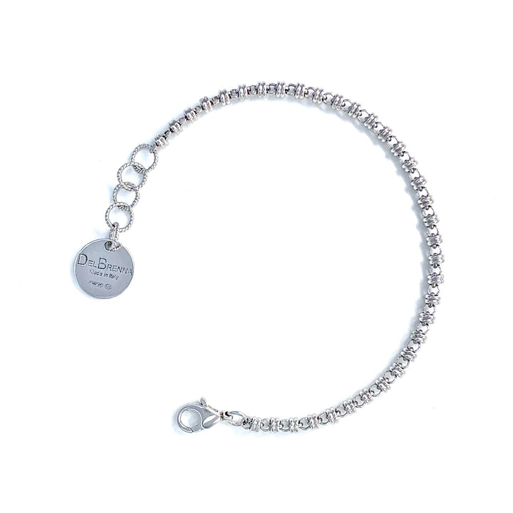 A silver chain bracelet with a round silver charm with the DelBrenna brand name against a white background. The silver bracelet has been handcrafted in Tuscany by DelBrenna Italian Jewelry artisans and designers. 