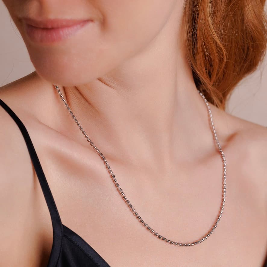 A side-facing, closeup view of a model wearing a short (18-inch) silver necklace. The necklace is a delicate 2MM version of the iconic silver chain designed by DelBrenna Italian jewelry designers in 1974 in Tuscany.