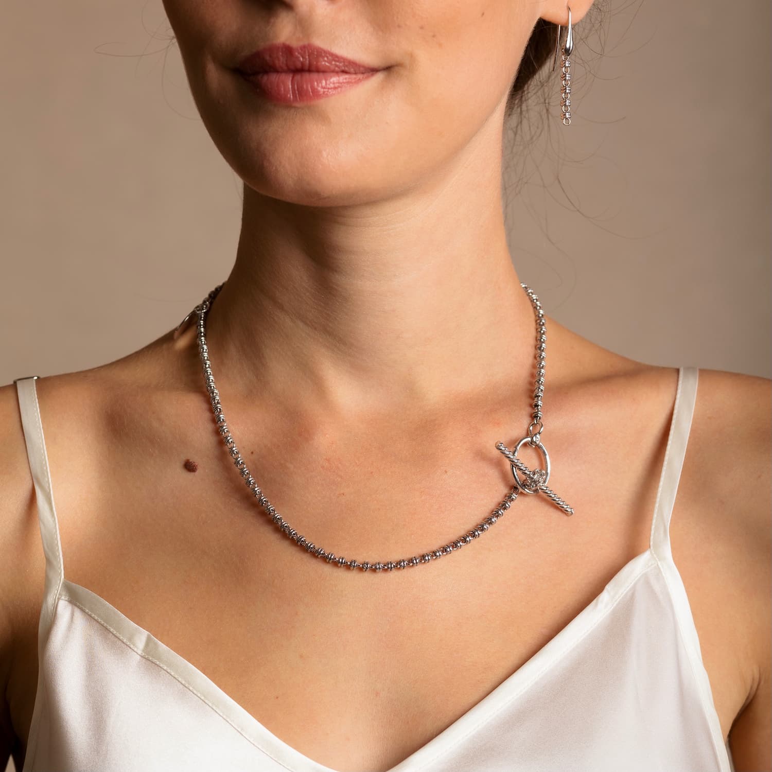 A model wearing a silver necklace with a toggle clasp and silver earrings to match the silver chain in the necklace - both from the Links 3mm collection from DelBrenna Italian Jewelry designers and artisans. Hand-crafted in Tuscany.