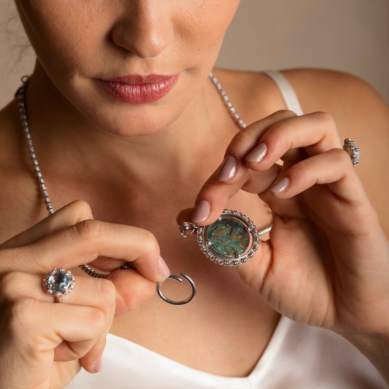 A model attaching a silver coin pendant to a silver necklace with a toggle clasp. She’s wearing silver earrings to match the silver chain in the necklace - both from the Links 3mm collection from DelBrenna Italian Jewelry designers and artisans. Hand-crafted in Tuscany.