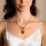 A model wearing a gold necklace with a toggle clasp with a gold heart pendant attached and gold earrings to match the gold chain in the necklace design - all are from the Links 3mm collection from DelBrenna Italian Jewelry designers and artisans. Hand-crafted in Tuscany.