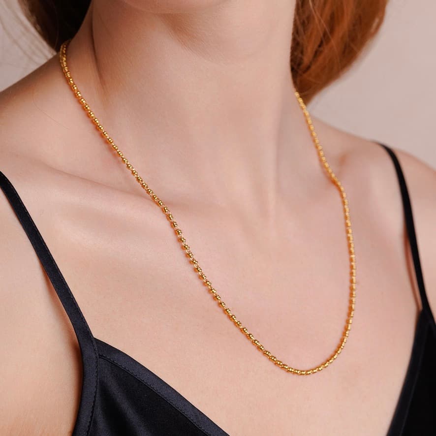 A left-facing, closeup view of a model wearing a short (18-inch) gold necklace. The necklace is a delicate 2MM version of the iconic gold chain designed by DelBrenna Italian jewelry designers in 1974 in Tuscany. 