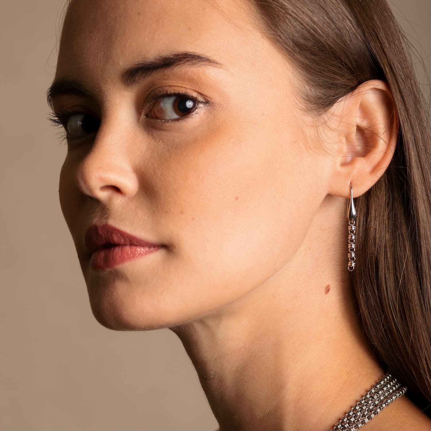 A model wearing long silver chain earrings designed and hand-crafted by DelBrenna Italian Jewelers in Tuscany. The earrings are designed based on the iconic Links collection of DelBrenna silver chains, necklaces, rings, and bracelets.