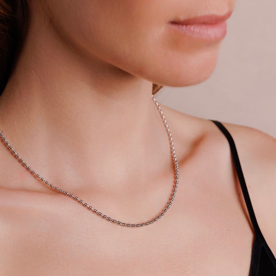 A side-facing, closeup view of a model wearing a short (16-inch) silver necklace. The necklace is a delicate 2MM version of the iconic silver chain designed by DelBrenna Italian jewelry designers in 1974 in Tuscany.