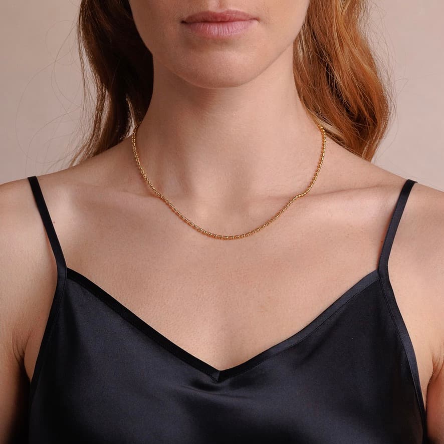 A front-facing, closeup view of a model wearing a short (16-inch) gold necklace. The necklace is a delicate 2MM version of the iconic gold chain designed by DelBrenna Italian jewelry designers in 1974 in Tuscany. 