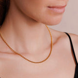 A left-facing, close-up view of a model wearing a short (16-inch) gold necklace. The necklace is a delicate 2MM version of the iconic gold chain designed by DelBrenna Italian jewelry designers in 1974 in Tuscany. 