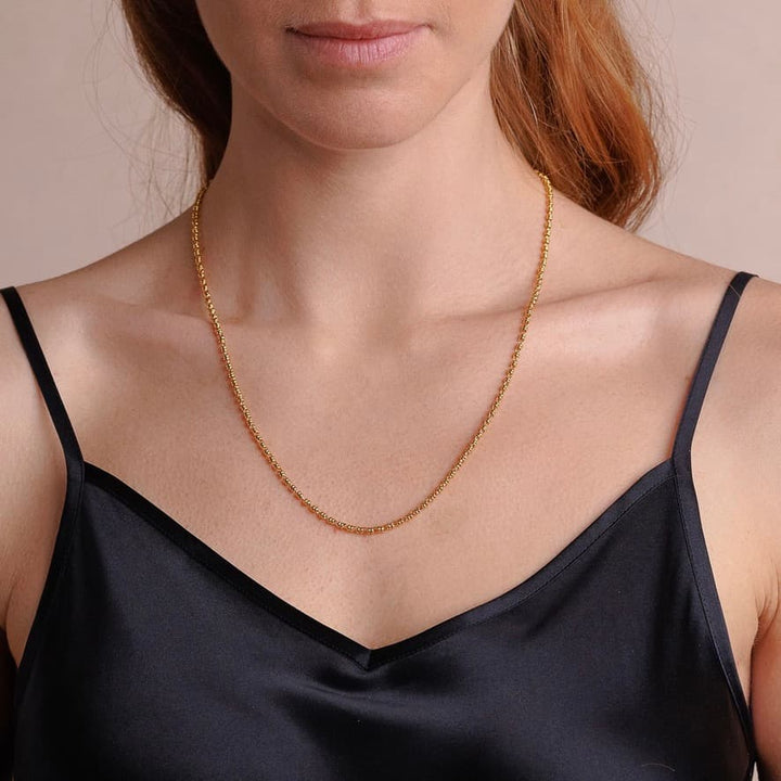 A front-facing, closeup view of a model wearing a short (18-inch) gold necklace. The necklace is a delicate 2MM version of the iconic gold chain designed by DelBrenna Italian jewelry designers in 1974 in Tuscany. 