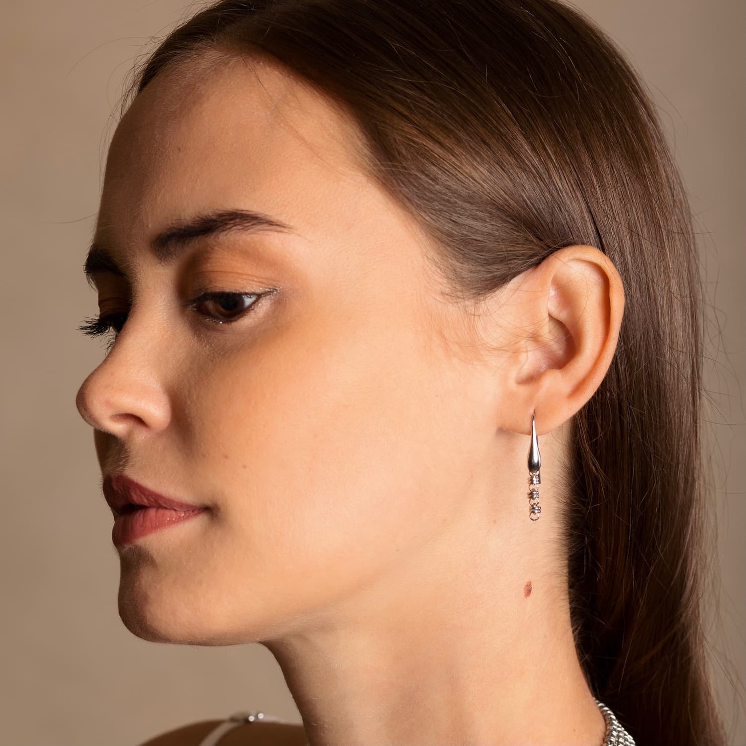 A model wearing silver chain earrings designed and hand-crafted by DelBrenna Italian Jewelers in Tuscany. The earrings and necklace shown here are designed based on the iconic Links collection of DelBrenna silver chains, necklaces, rings, and bracelets.