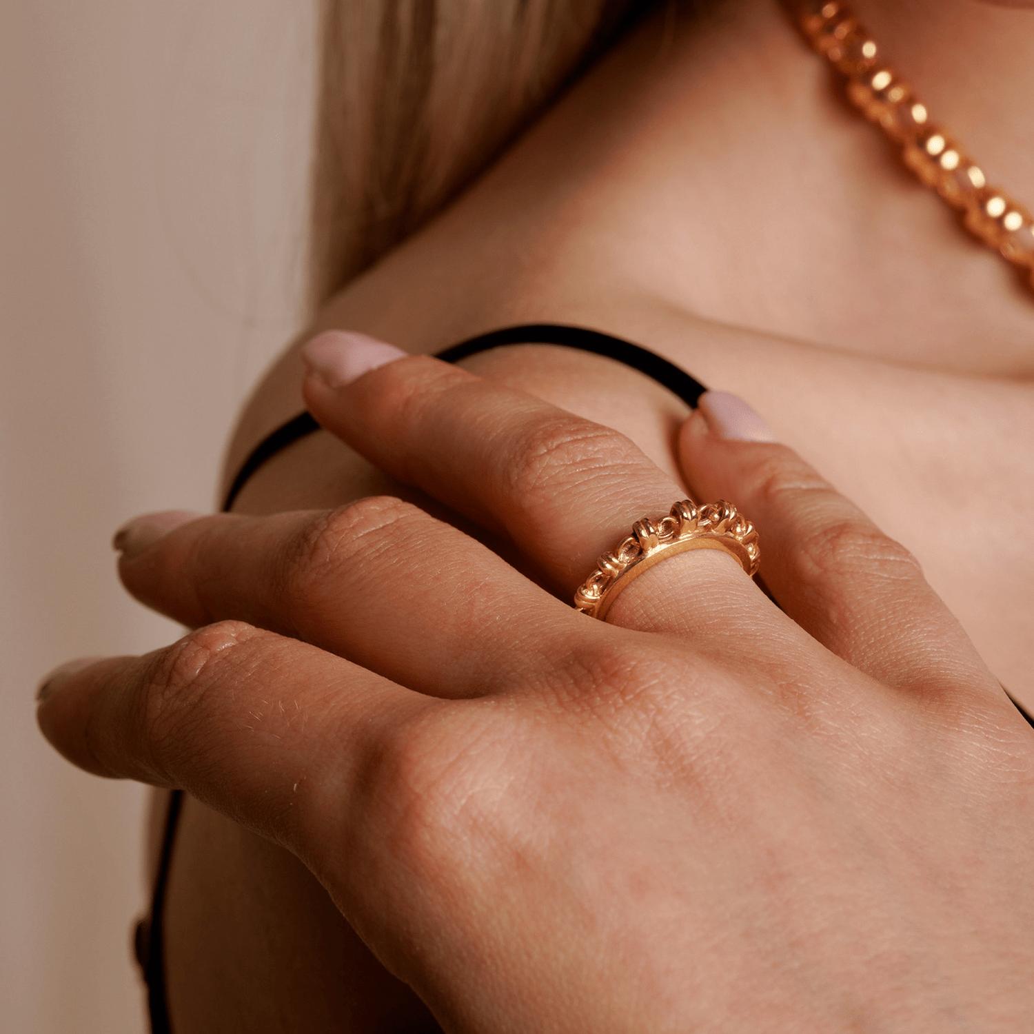 A closeup of a model wearing a gold ring with a gold chain design that has varying sizes of links to resemble a climb to the top - thus its Italian name ‘Scalare’: to climb. Designed and hand-crafted by DelBrenna Italian Jewelry designers and artisans in Tuscany.  