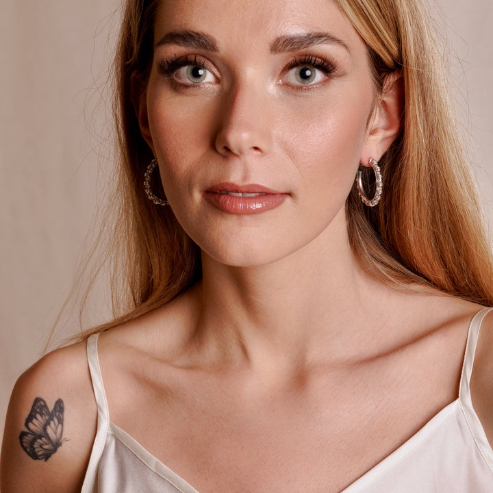 A model wearing large silver hoop earrings with a chain design from DelBrenna Italian jewelry design. The earrings are hand-crafted in Tuscany. 