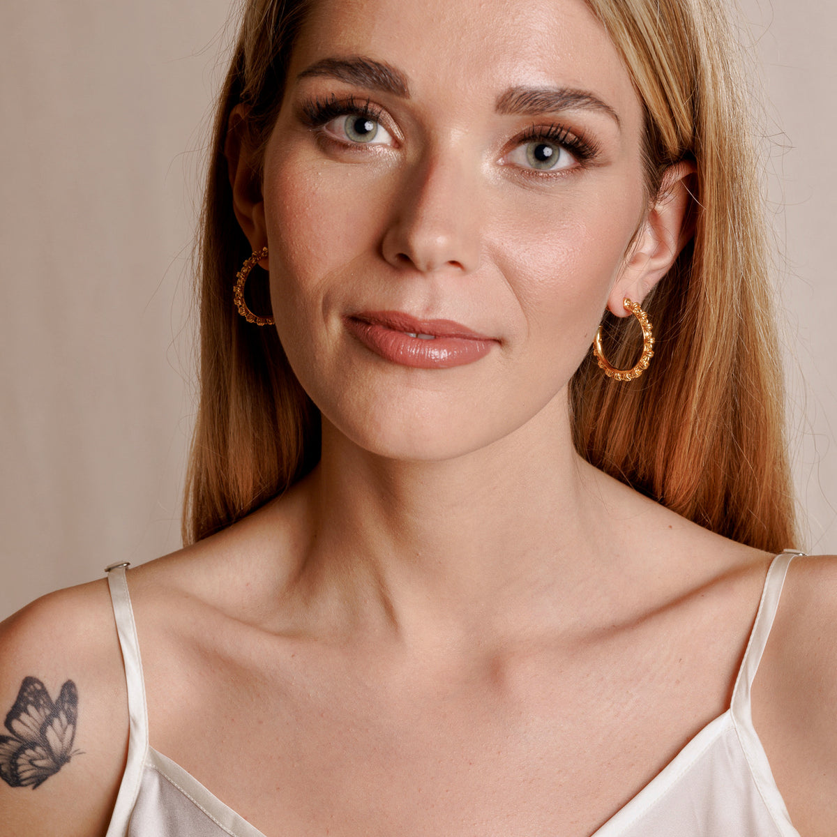 A model wearing large gold hoop earrings with a chain design from DelBrenna Italian jewelry design. The earrings are hand-crafted in Tuscany. 